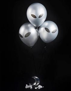 three balloons with faces on them are floating in the air next to some white marshmallows