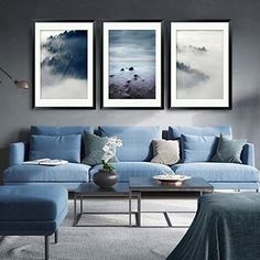 a living room with blue couches and paintings on the wall above them, along with a coffee table