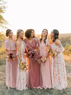 a group of women standing next to each other in long dresses and holding bouquets