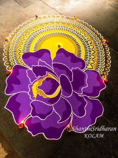 a purple and yellow flower on the ground with an orange circle around it that says happy diwali