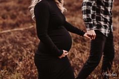 a pregnant woman standing next to a man in a field