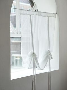 a window with white curtains hanging from it's side