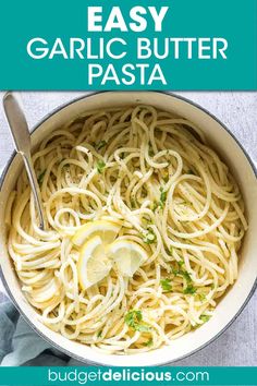 a bowl filled with garlic pasta and topped with lemon wedges, parsley and parsley