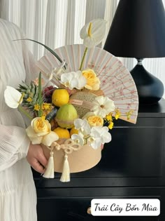 a woman holding a bouquet of flowers next to a black table with a fan on it