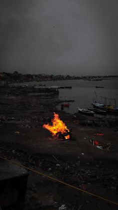 a fire in the middle of a body of water with boats on it at night