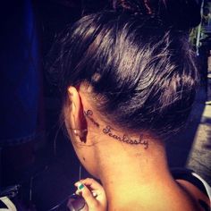 the back of a woman's neck with an inscription behind her ear