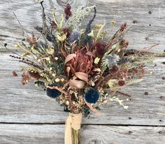 a bouquet of dried flowers sitting on top of a wooden table