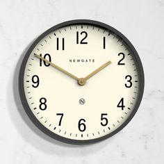 a black and white clock with gold hands on a marble counter top, next to the words newgate