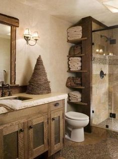 a bathroom with a toilet, sink and shower in it's own area next to a wooden shelf filled with towels