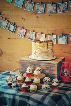 a table topped with lots of cupcakes next to a cake on top of a wooden box