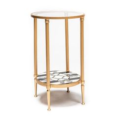 a round table with a glass top and gold trimmings on the bottom, against a white background