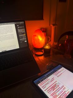 an open laptop computer sitting on top of a desk next to a lit up lamp