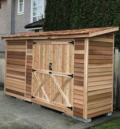 a wooden storage shed sitting in front of a house