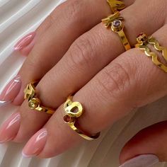 a woman's hand with three rings on her fingers and one ring in the shape of a skull