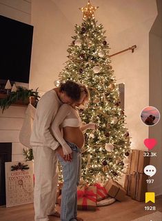 a man and woman standing in front of a christmas tree