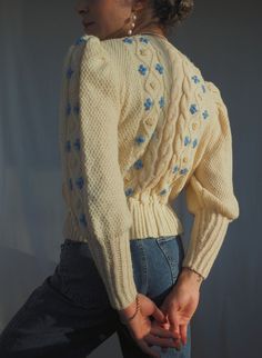 a woman in jeans and a sweater is holding her hands behind her back as she poses for the camera