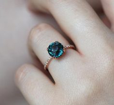 a woman's hand with a ring on it and a blue stone in the middle