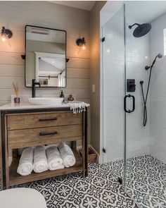 a bathroom with a sink, toilet and shower stall in the middle of it that has black and white tiles on the floor