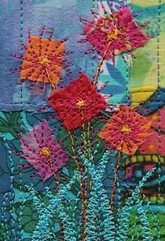 some very pretty flowers on a patchwork piece of fabric with stitching in the middle