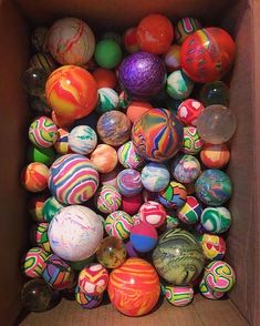 a cardboard box filled with lots of different colored marbles on top of each other