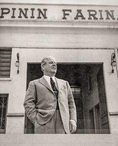 black and white photograph of a man standing in front of a building with the words pininfarina on it