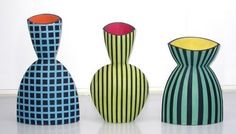 three colorful vases sitting next to each other on a white surface with windows in the background