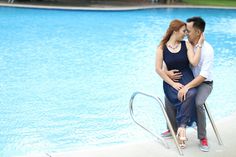 a man and woman sitting next to each other near a swimming pool