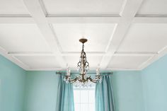 a room with blue walls and white ceilinging has a chandelier hanging from the ceiling