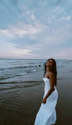 a woman in a white dress standing on the beach