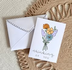 two cards with flowers on them sitting next to each other and the words thinking of you written in cursive writing