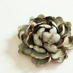 a flower shaped brooch sitting on top of a white table