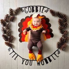 a baby dressed as a turkey laying on top of a sign