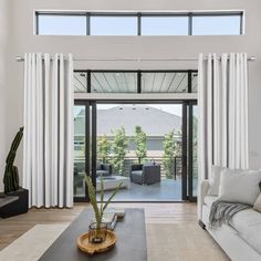 a living room with white couches and large windows