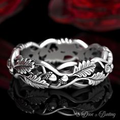 a silver ring with leaves and flowers on the inside, in front of a black background