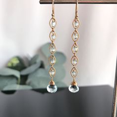 "These Blue Topaz teardrops perfectly capture the clarity of an early morning mist on the Sea. In some light they appear almost clear and in other, have a piercing gray/blue. Both the faceted central stone of the drop and the faceted smaller Rondelles have been handpicked and matched for their clarity and tone. Each round link, in either 14K Gold Fill or Sterling Silver, has one of these Topaz Rondelles nestled in its embrace. Balanced against these links is the Blue Topaz tear drop at its base. Elegant Briolette Gemstone Chandelier Earrings, Elegant Crystal Drop Earrings With Gemstone, Elegant Pierced Briolette Earrings, Long Drop Chandelier Earrings For Anniversary, Elegant Gemstone Linear Dangle Earrings, Elegant Gemstone Dangle Linear Earrings, Elegant Dangle Linear Earrings With Gemstones, Elegant Gemstone Chandelier Earrings With Long Drop, Elegant Gemstone Dangle Chandelier Earrings