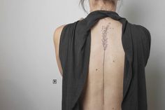 the back of a woman's neck with a flower tattoo on it