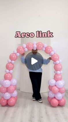 a man standing in front of a pink and white balloon arch with the words afro link on it