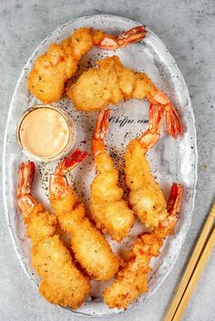 fried shrimp and dipping sauce on a plate with chopsticks