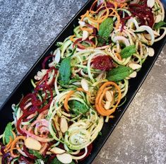 a black tray filled with assorted veggies on top of a gray table