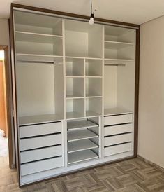 an empty walk in closet with white shelves and drawers