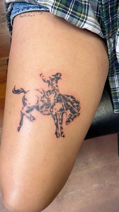 a woman's leg with a tattoo of a cowboy riding a horse on it