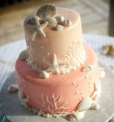 a three tiered cake decorated with seashells and starfish on a table