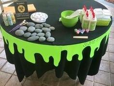 a table with green and black paint on it, surrounded by other items such as candles