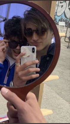 a woman taking a selfie in front of a mirror with her cell phone and sunglasses on