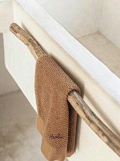 a towel hanging on the side of a white wall next to a wooden stick and toilet paper