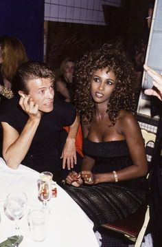 a man and woman sitting at a table with wine glasses in front of their faces