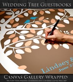 a person writing on a wedding guest book with a pen in their hand and a tree painted on the cover