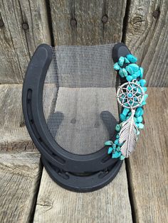 a black horseshoe with turquoise beads and a feather on it