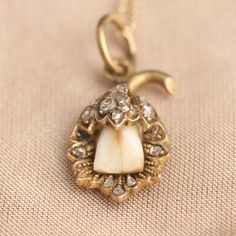 The use of baby teeth (or "milk teeth") in jewelry has nothing to do with mourning. Quite the opposite - during the last centuries, it was worth celebrating if your child survived long enough to lose her first teeth. Thus, the Victorians (a sentimental and not-too-squeamish bunch) commissioned jewelry made from these tiny treasures. This unusual, exquisite pendant features a milk tooth in a detailed floral mounting accented by 14 sparkly rose cut diamonds. Hangs from a new 18" 14k gold chain. Human Teeth Jewelry, Fairy Jewellery, Tooth Keepsake, Victorian Baby, Milk Teeth, Tooth Ring, Teeth Jewelry, Victorian Photos, Edwardian Jewelry