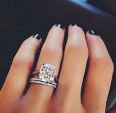 a woman's hand with two rings on her fingers and a diamond in the middle